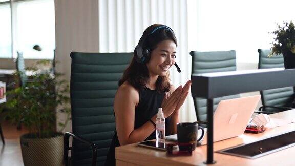 一位亚洲华裔美丽的女白领戴着口罩对着摄像机进行视频通话与他的商业伙伴进行视频会议