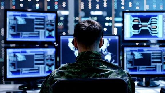 军事技术支持专业人员使用耳机进行指导的回顾他在监控室工作里面摆满了显示各种信息的显示器