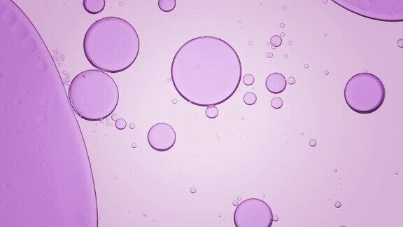 紫色气泡在清澈的液体中移动到左边还有较小的气泡