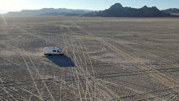 无人机视图改装的短跑露营车行驶在中午的博纳维尔盐滩中部
