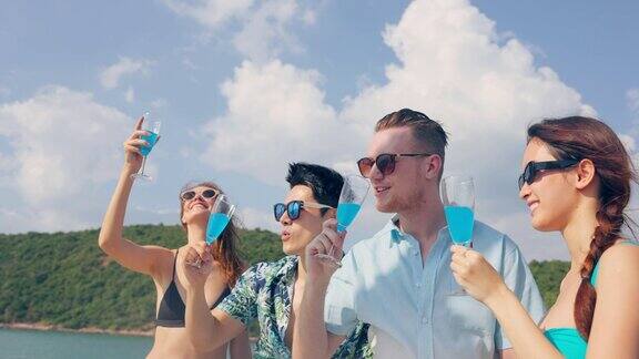 一群不同的朋友在游艇上喝香槟聚会迷人的年轻男人和女人挂在一起庆祝假期度假旅行而双体船航行在夏天日落