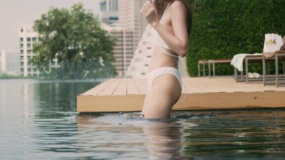 美丽的亚洲女孩穿着泳装玩在酒店的游泳池在周末