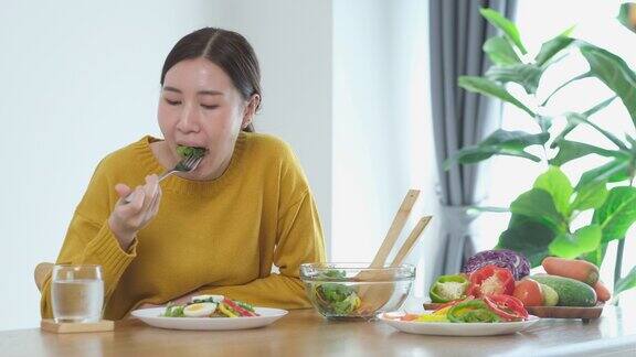 年轻的亚洲妇女在家里吃沙拉