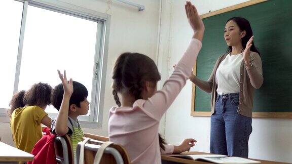 亚洲学校老师与学生举手在学校工作的年轻女子举起手臂学校的孩子们举起双手回答问题热情、渴望、享受