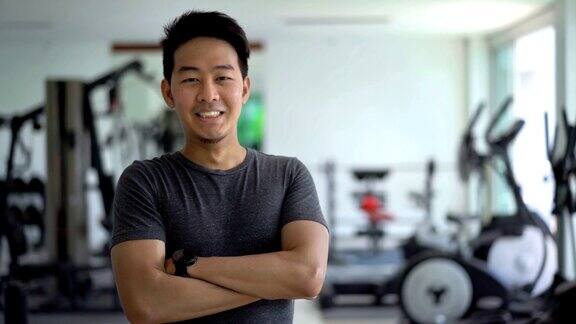 亚洲男人双臂交叉在健身房微笑