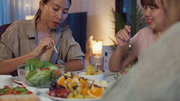 年轻的亚洲女性朋友晚上坐在家里餐厅的餐桌上吃沙拉和聊天的特写生活方式健康饮食享受自然生活和植物性饮食