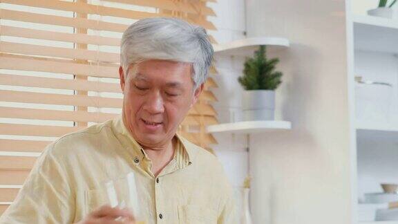 亚洲老年人在家厨房喝橙汁退休生活方式积极的老年人健康