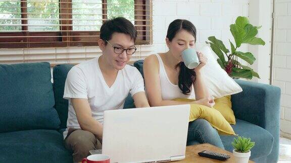亚洲夫妇家庭放松在沙发上工作的笔记本电脑商业财务