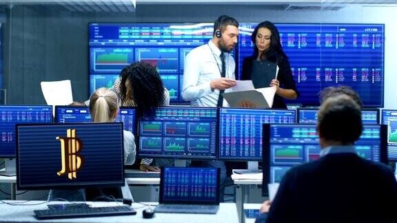 多种族交易员团队在证券交易所办公室忙于加密货币工作交易商和经纪人在市场上买卖股票显示器显示相关的信息图数据和数字