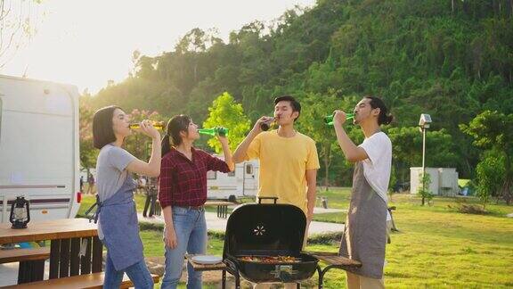 一群亚洲男女在晚上一起举行户外新年派对朋友们喝着一瓶啤酒带着幸福和微笑喝着旅行自然露营车露营