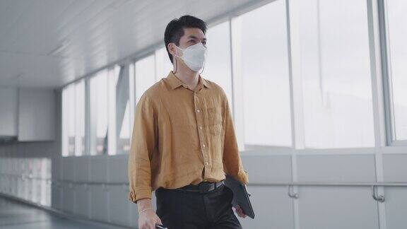 一位亚洲商人在机场的走廊上走着他正在出差