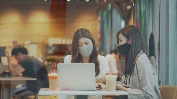 两个亚洲女性在商务会议上一起使用笔记本电脑进行讨论