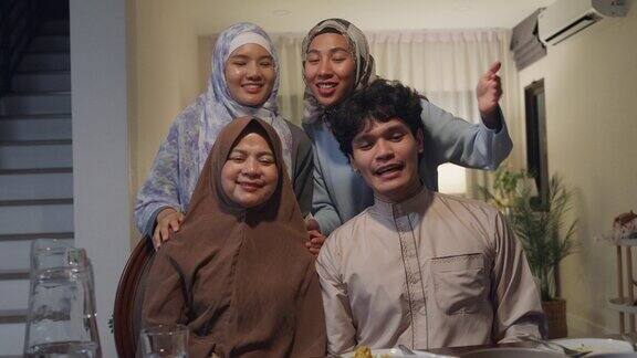 快乐的亚洲穆斯林家庭在线问候庆祝与表弟遥望摄像机视频一起在家叫斋月晚餐一起庆祝开斋节