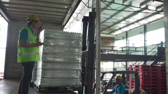亚洲仓库工人用叉车将纸箱装到托盘上领班清点存货