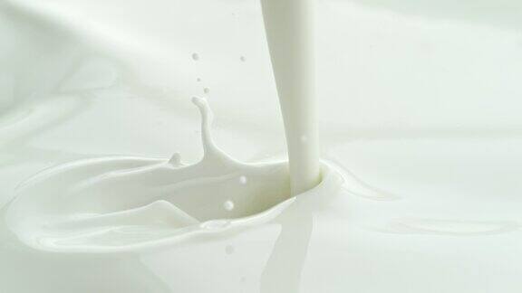 将牛奶倒入白色奶油液体中在微距和慢动作中产生飞溅和波浪