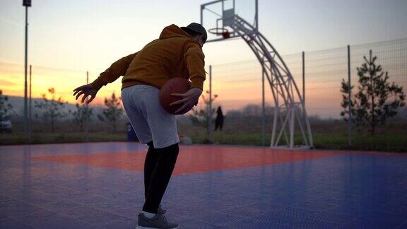 一个十几岁的男孩在户外运动场上打篮球