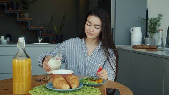 亚洲妇女倒牛奶在碗在家里厨房早餐慢动作