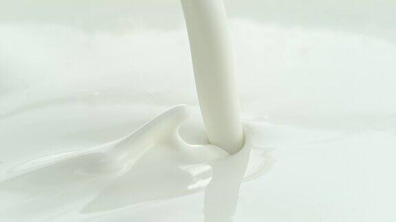 将奶油牛奶倒入白色液体中在微距和慢镜头中飞溅