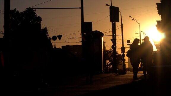 日落时城市街道上人影和汽车的剪影