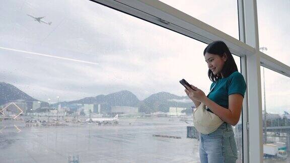 玩手机通讯在候机楼内等候登机的女子旅行