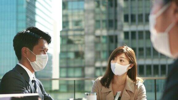 在亚洲商务人士开会时要戴着防护面具保持社交距离