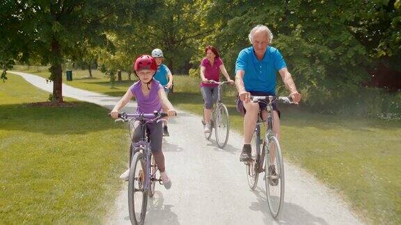 孙辈们和祖父母们骑着自行车穿过公园