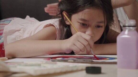 亚洲少女在家里的时候在客厅里画她的艺术和工艺她用水彩和画笔在白纸上创作艺术项目形成自己的想象艺术和工艺概念