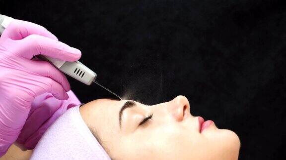 女性美容师在病人脸上使用超声波洗洁精专业的超声波设备面对整容手术