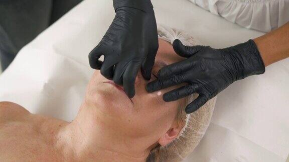 一位美容治疗师将胶原蛋白垫置于客户眼睛下的俯视图抗老化美容程序概念