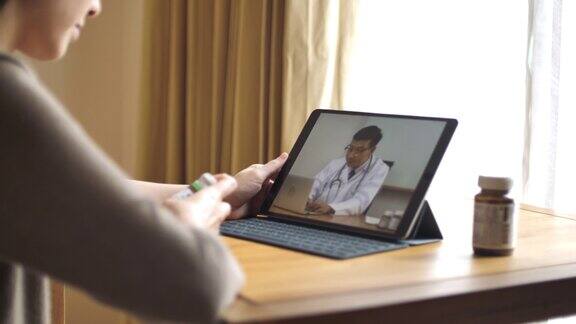 女病人在家里用数字平板电脑与资深医生交谈