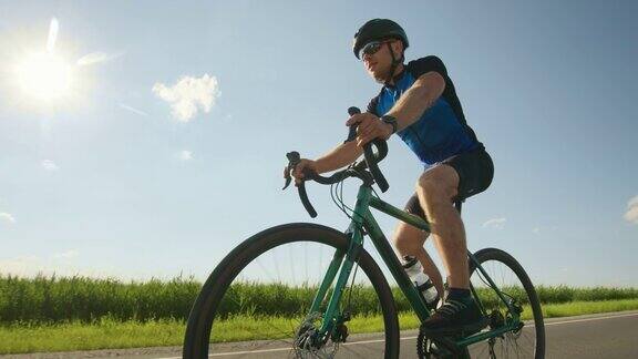 一个骑自行车的运动员正沿着跑道慢慢地骑行骑自行车训练太阳在背景中闪耀4k