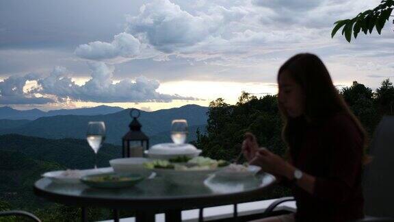 模糊的一个年轻女子在阳台上吃饭有美丽的山景