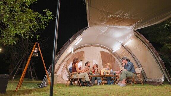 一群不同的朋友一起在帐篷里进行户外露营派对迷人的年轻男女旅行者喝着酒精啤酒享受假期期间在森林里闲逛度假旅行