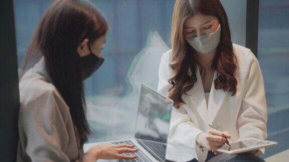 两个亚洲商业女性使用笔记本电脑互相建议