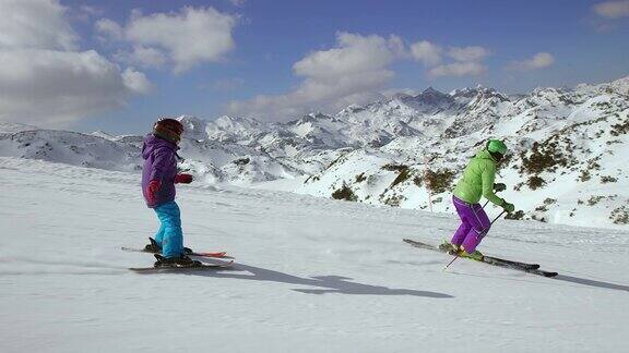 小女孩在滑雪教练后面滑雪