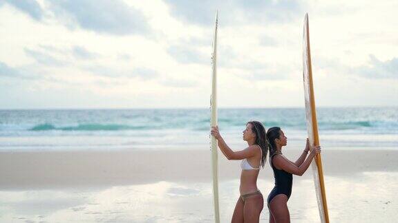 4K肖像的亚洲女性朋友抱着冲浪板在热带海滩在夏季日落