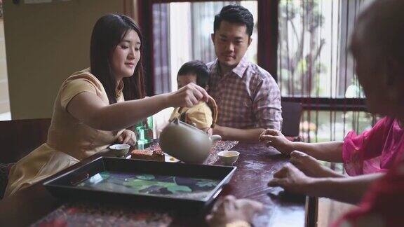 中国女儿在多代同堂期间喝茶享用传统的节月饼和下午茶聚会期间在家喝茶