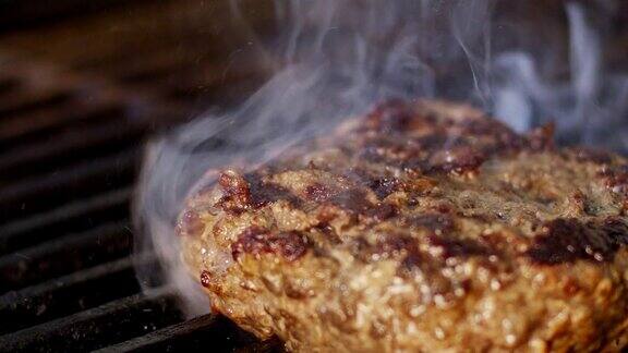 慢动作的牛肉汉堡在烧烤在近距离与火焰和烟雾