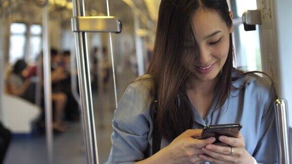 使用手机亚洲女性在地铁上使用手机