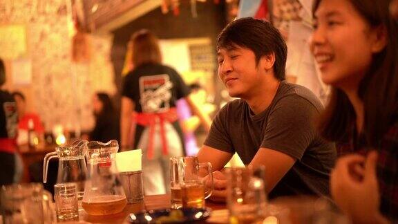 亚洲男子喜欢在居酒屋酒吧喝酒和听他的朋友开玩笑
