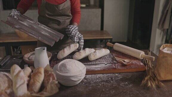 面包师把刚烤好的面包从烤箱里拿出来放在桌子上