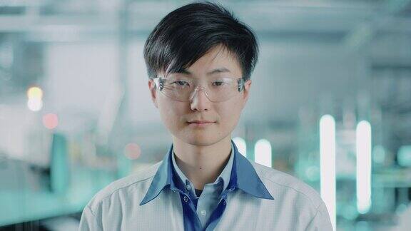 关于高科技工厂:亚洲工人穿着制服和护目镜的肖像在背景模糊的电子装配线与明亮的灯光