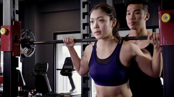 年轻的亚洲肌肉女性举下蹲杠铃在健身房生活方式运动和健美