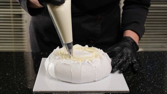 糕点师用糕点袋填满奶油布朗尼安娜·巴芙洛娃蛋糕的制作过程
