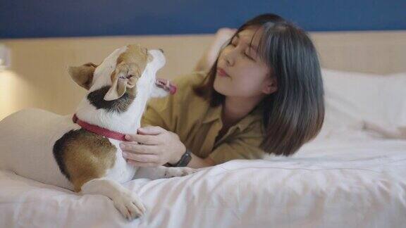 一个年轻的亚洲女人躺在床上被她的狗舔了脸