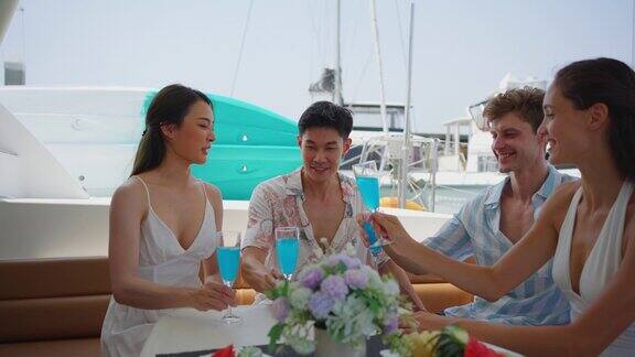 一群不同的朋友在游艇上开派对喝着香槟迷人的年轻男女聚在一起庆祝节日双体船在夏日夕阳下航行