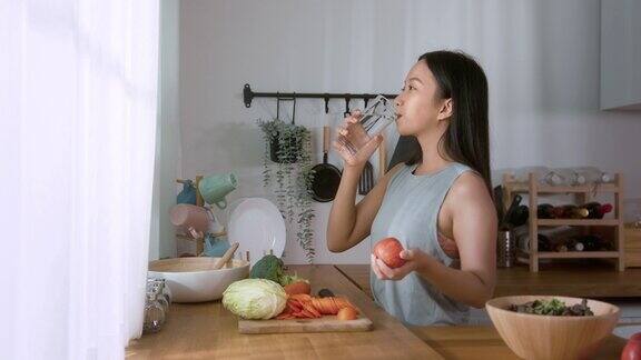一名亚洲年轻女子在家里的厨房里喝淡水