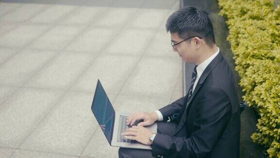 亚洲商人在街角使用笔记本电脑