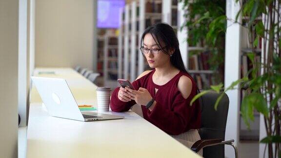 认真的学生女孩准备考试使用笔记本电脑在大学图书馆进行远程教育