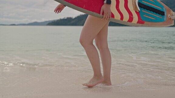 女子手持冲浪板在沙滩上行走的特写镜头